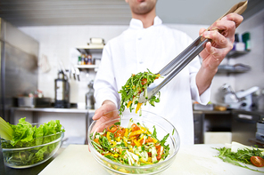 Chef taking salad from bowl to serve