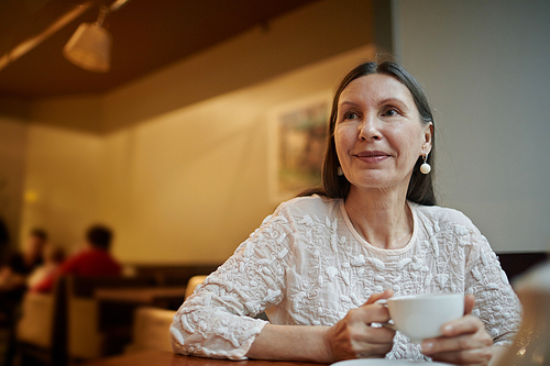 Mature woman with long hair drinking tea in cafe