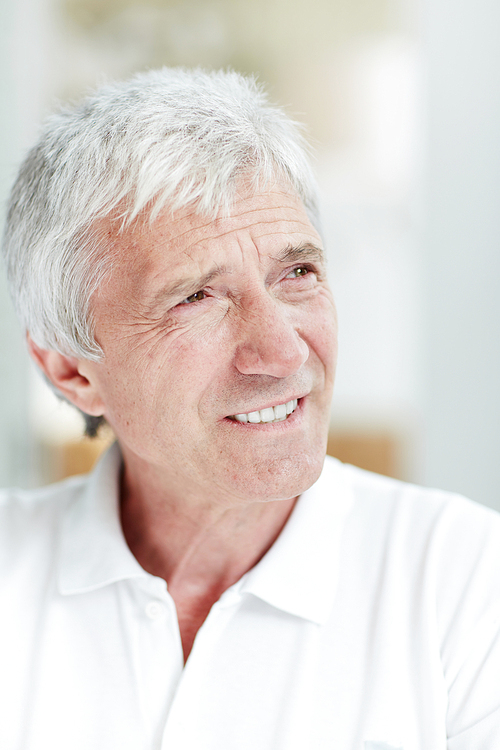 Senior man with toothy smile and grey hair staring aside at something curious