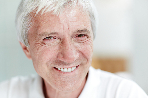 Friendly aged man with grey hair and toothy smile looking at you