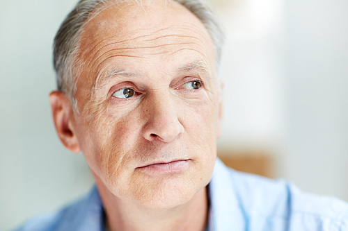 Head of calm mature man looking aside at something curious