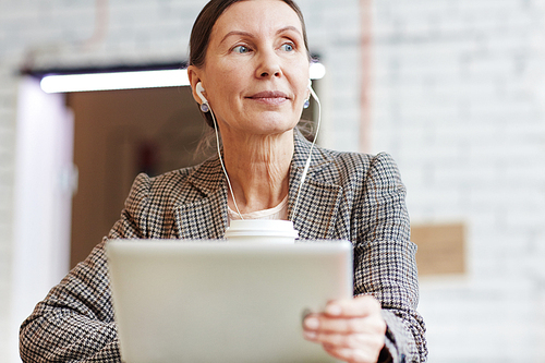 Mature female with touchpad listening to music at break