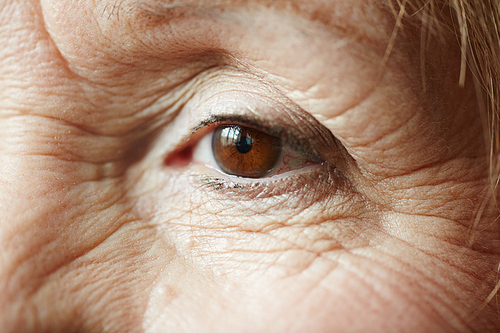 Extreme close-up shot of old female eye with minimal make-up looking away pensively