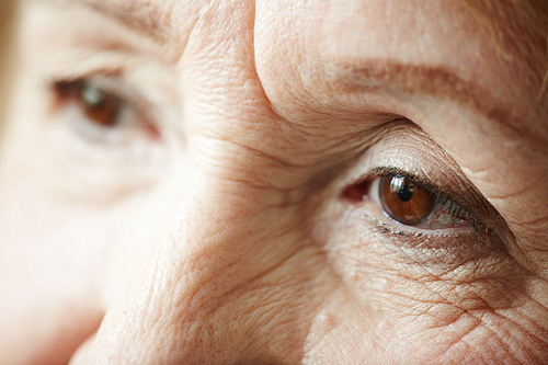 Retired woman with tired glance full of sadness looking away, extreme close-up shot