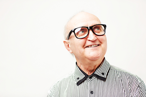 Portrait of happy old gentleman in eyeglasses and striped shirt smiling and looking up isolated on white