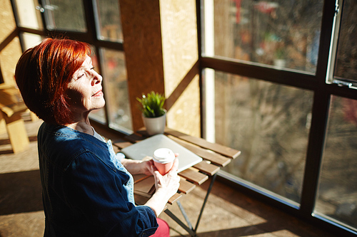 Delighted woman with drink enjoying sunny morning