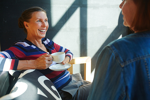 Restful female with cup of tea or coffee having talk with buddy