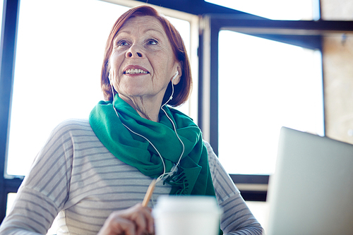 Elderly female with earphones listening to music at leisure