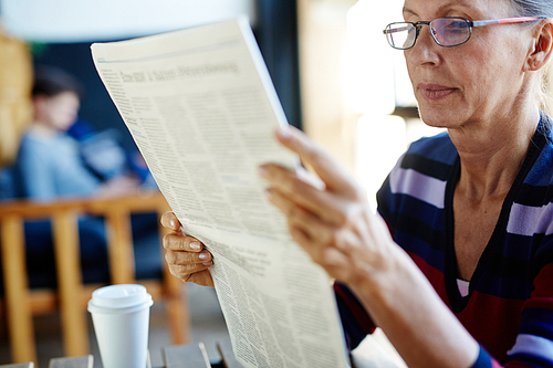 Serious mature female concentrating on reading news