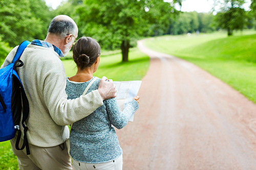 Affectionate seniors standing by country road with map during their trip