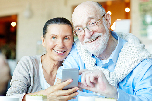 Mobile senior couple browsing in the net through smartphone