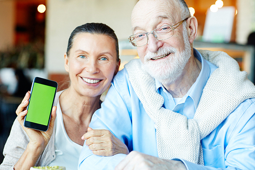 Senior woman showing her gadget with husband near by