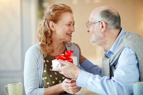 Senior man giving box with surprise to his wife