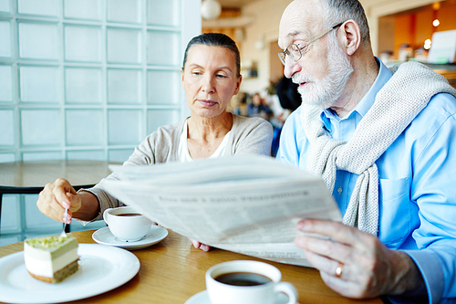 Modern seniors discussing latest news by dessert in cafe