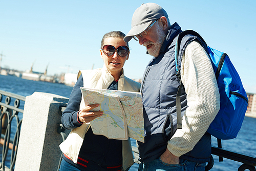 Senior woman and her husband looking at map while traveling