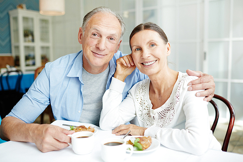 Happy retired couple spending time in cafe and having dessert with tea