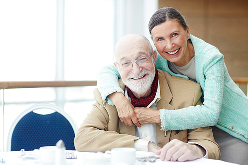 Amorous seniors sitting by served table in cafe or restaurant