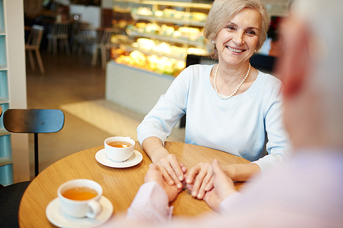 Happy senior woman looking at her husband and talking to him in cafeteria