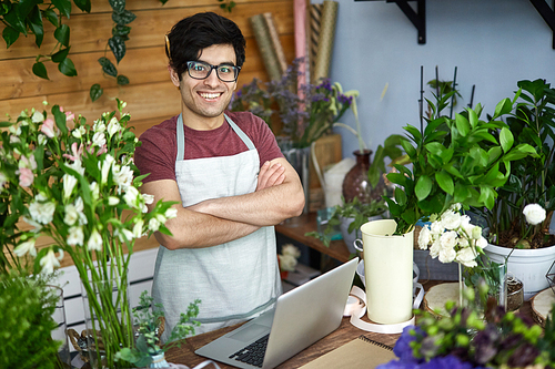 Young vendor of flowers standing by counter in flower-shop