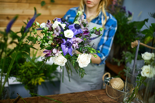 Woman arranging floral bouquet from fresh flowers