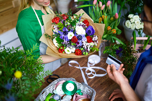 Florist with bouquet and her client paying for flowers
