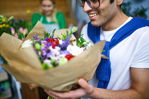 Guy smelling bouquet of flowers in florist store