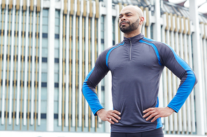 Strong man in sportswear standing in akimbo pose