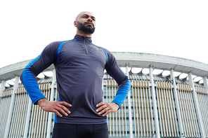 Sportive guy with his arms akimbo against modern edifice