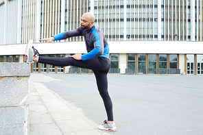 Young athlete exercising on background of urban edifice