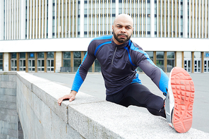 Young man in activewear practicing physical exercises outdoor