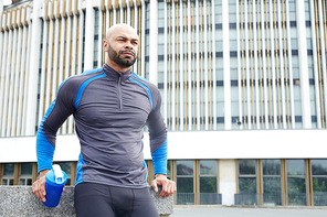 Calm athlete with plastic bottle having short rest before new training