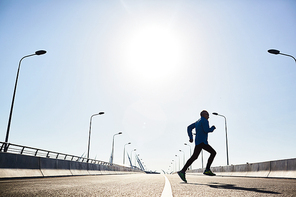 Low angle view of confident aged sportsman going in for sports while having outdoor workout, cloudless blue sky on background