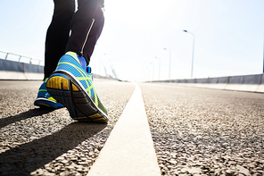 Feet of active man during morning workout on urban road