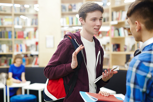 Assignment Guys Two guys discussing book or home assignment in library | 유토이미지 | 상세페이지 ...