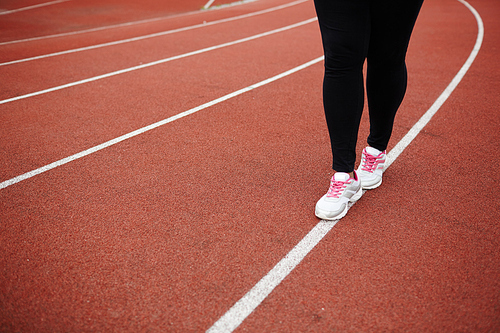 Legs of plus-sized woman walking down white line on stadium