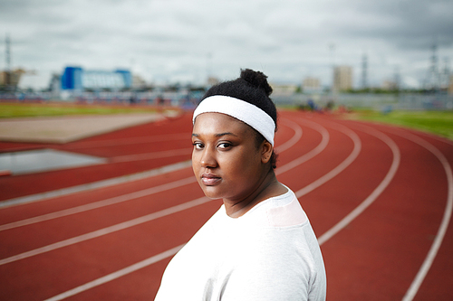 African-american overweight girl in activewear on background of stadium