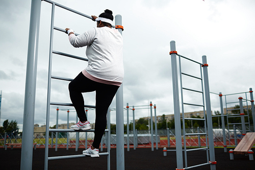 Young woman in sportswear ascending on sports facilities on stadium