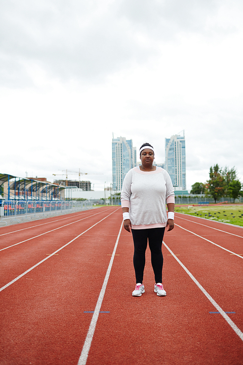 Young plump woman in activewear standing on one of racetracks