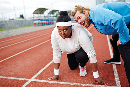 Personal trainer motivating overweight woman preparing for run on starting line