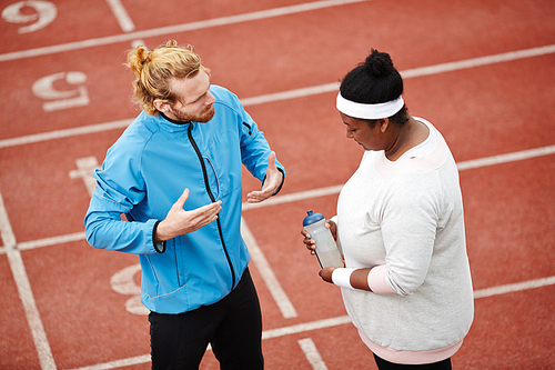 Run instructor giving recommendations to young sporty plump woman before marathon