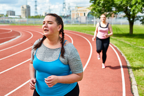 Exhausted fat woman going on running in spite of tiredness