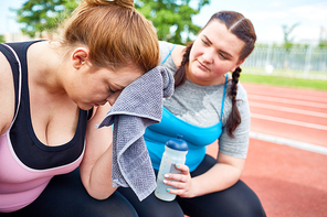 Unhappy and exhausted female with towel and her friend near by