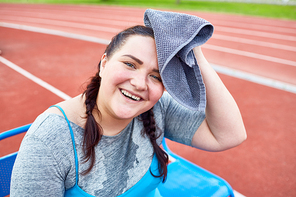 Sweaty and happy fat woman drying her forehead with towel after hard workout