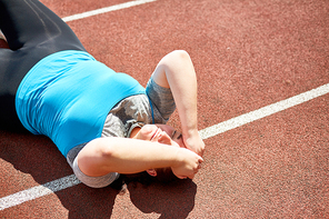 Exhausted sweaty over-size woman trying to do difficult exercise on race track