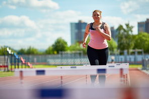 Chubby woman running on stadium while taking part in marathon