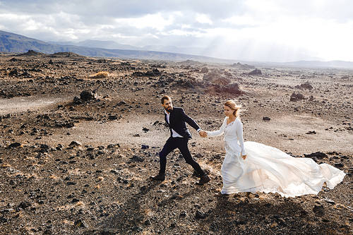 Young newlyweds walking down plain land of Iceland