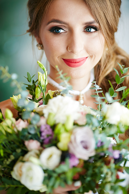 Beautiful bride with piercing in nose holding bunch of flowers