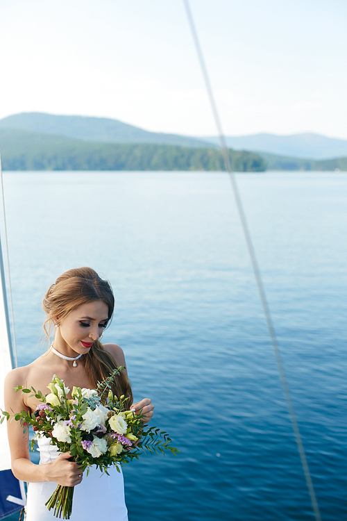 Bride with rose bunch on background of lake
