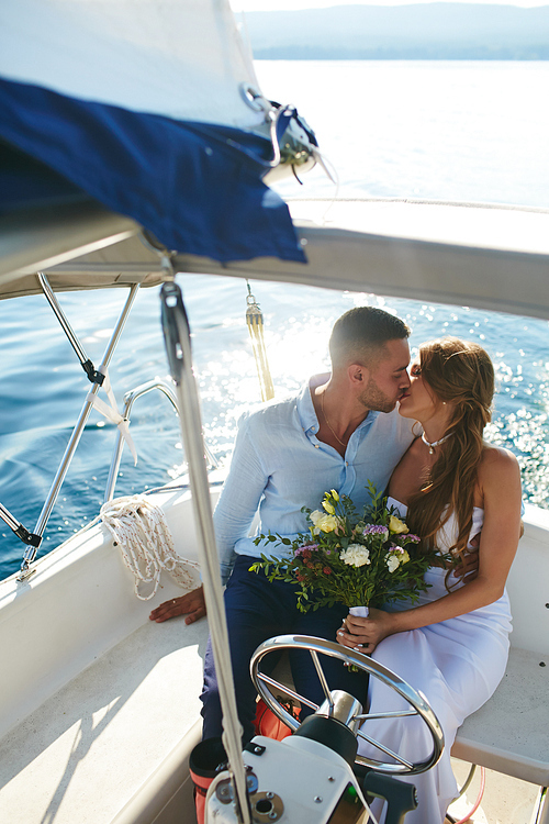 Bride and groom kissing while traveling on yacht