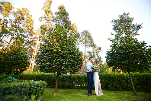 Bride and groom standing on green grass in garden